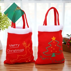 Détail de sacs cadeaux de Noël en velours rouge avec renne et sapin brodés en or