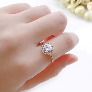 Elegant rose gold engagement ring with round halo diamond setting on a floral background