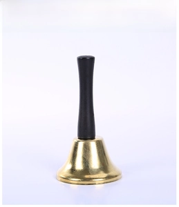 Gros plan d'une cloche à main classique en métal doré avec un long manche noir festif