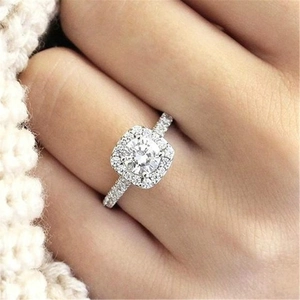 Silver square-cut cubic zirconia ring with diamond halo and pavé band worn on finger
