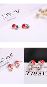 Macro view of Christmas snowman hat earrings with red enamel and sparkling pear-cut zircon