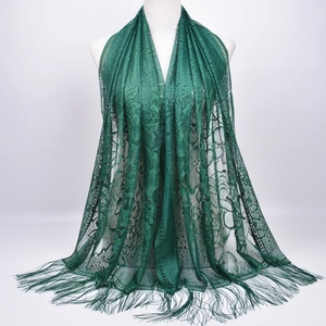 Close-up of dark green lace shawl featuring hollow floral patterns and fringe details