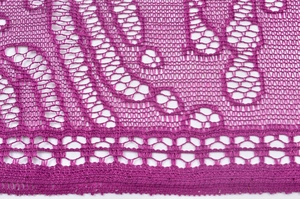 Macro view of magenta lace scarf detail with hollow floral patterns and jagged edges