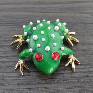 Detailed close-up of a green enamel frog brooch with white pearls and red rhinestone eyes