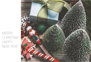 Mini snow-dusted Christmas trees with reindeer figurine and gift box on wood