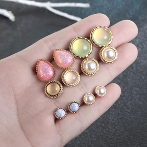 Close-up of assorted resin and pearl stud earrings set held in palm for size scale