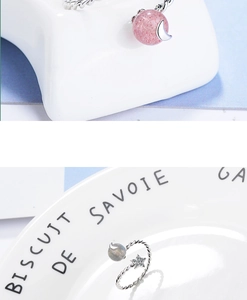 Detail view of silver rings featuring strawberry quartz and a sparkling moon pendant