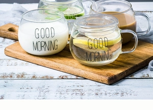 Mugs en verre résistant avec poignée et texte Good Morning sur une table de petit-déjeuner
