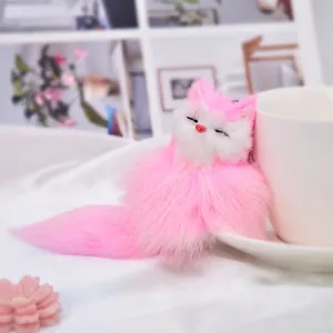 Cute pink and white plush fox keychain leaning on a white ceramic cup for bag decor