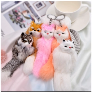 Detailed set of five colorful plush fox keychains with fluffy tails on white silk fabric