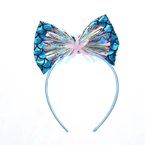 Détail d'un serre-tête sirène bleu avec nœud à écailles et décorations en forme d'étoile