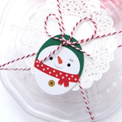 Macro detail of octagonal transparent cupcake box with snowman tag and red cotton bow