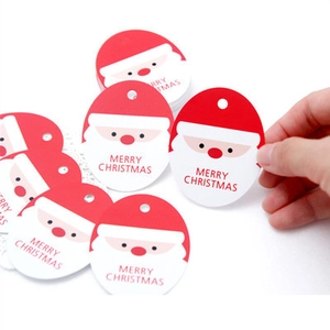 Detail view of festive Santa-shaped paper gift tags with Merry Christmas typography