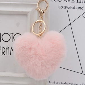 Close-up of fluffy pink heart keychain with golden metal clasp and soft plush texture
