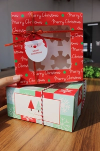 Detail of red and green Christmas cupcake boxes with clear windows and festive ribbons