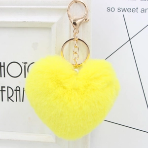 Close-up of a fluffy yellow heart pom pom keychain with a gold metal lobster clasp