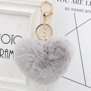 Detailed view of gray heart-shaped plush keychain with golden metal ring and buckle