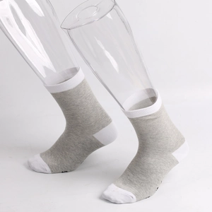 Detail view of grey and white mid-calf socks with ribbed cuffs on a display leg model