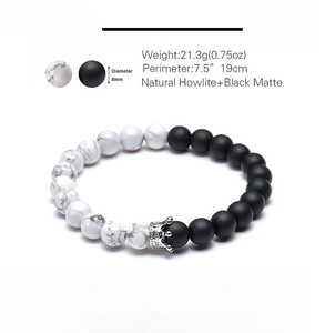 Detail view of 8mm natural howlite and black matte stone bracelet with crown charm