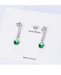 Macro view of silver drop earrings with green star-shaped faux gems on display card