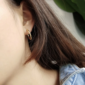 Detailed close-up of a polished gold irregular hoop earring worn by a model in casual style