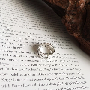 Macro detail of 925 sterling silver ring with geometric crown pattern on book page