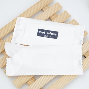 Individual disposable wet wipes in white packaging on a decorative wooden tray