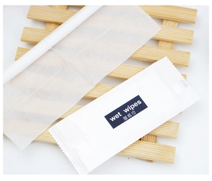 Macro detail of individually wrapped non-woven wet wipes on a wooden tray