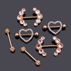 Macro shot of rose gold piercing jewelry with heart-shaped zircon on black mirror