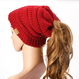 Thick knit ponytail beanie in dark red featuring a C.C leather patch and top opening