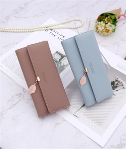 Detailed view of PU leather long wallets with gold leaf pendants on a marble background