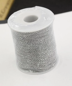 Macro shot of a 1.5mm silver square cross chain spool wrapped in transparent plastic