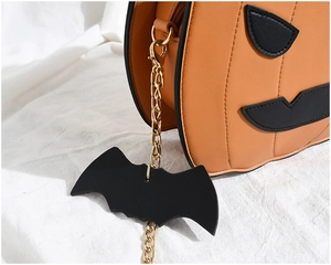 Detail of pumpkin crossbody bag with gold chain and black bat charm for Halloween