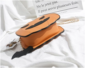 Detail view of orange pumpkin bag with golden chain and black bat charm decoration