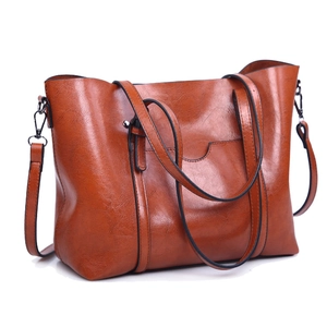 Detail of brown leather tote bag showing texture, front pocket and detachable strap
