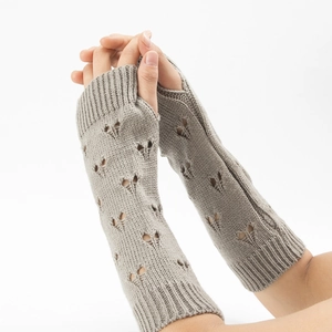 Detail of knitted arm warmers in taupe with hollow heart pattern and fingerless design