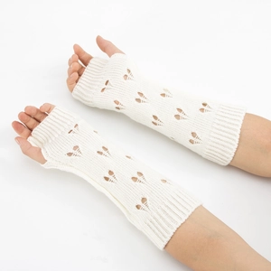 Close-up of ivory knitted arm warmers with heart cutouts and thumb hole design