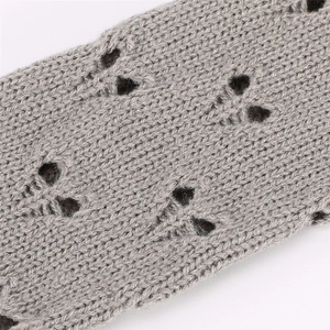 Macro shot of grey knit arm warmers showing detailed openwork hollow knitting texture