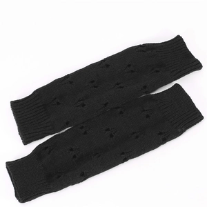 Detail of black knitted arm warmers featuring an openwork pattern and long thumbhole cuff