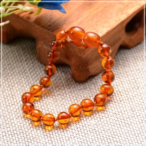 Detail of natural Baltic amber bead bracelet with round and oval beads on white fabric
