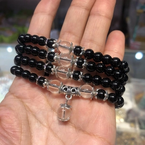 Close-up of four black bead bracelets with clear glass accents held in a hand