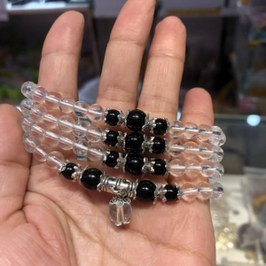 Detail of four layered beaded bracelets with clear and black beads on a wrist