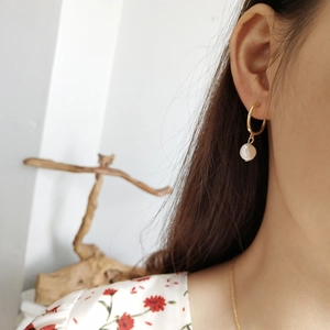 Close-up of model wearing 925 silver golden hoop earrings with irregular freshwater pearls