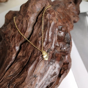 Detailed view of a golden heart pendant necklace hanging on a textured wooden background