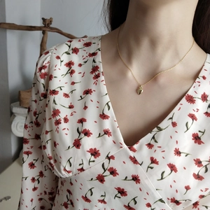 Elegant gold heart pendant necklace on model wearing a floral V-neck summer dress