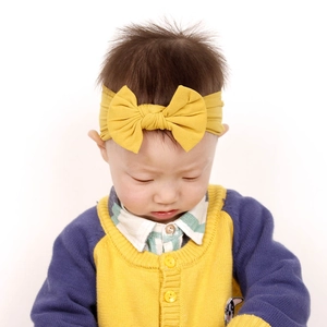 Dettaglio della fascia per neonata in nylon giallo senape con fiocco elastico