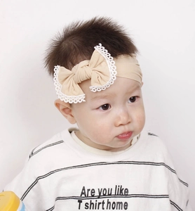 Detailed macro view of a soft nylon baby headband featuring a lace-trimmed bow design
