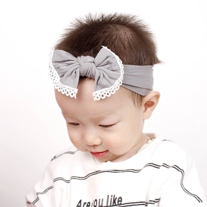 Detail of grey soft nylon baby headband featuring a large bow with white lace edges