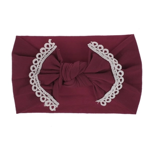 Close-up of soft burgundy nylon baby headband with a delicate white lace bow detail