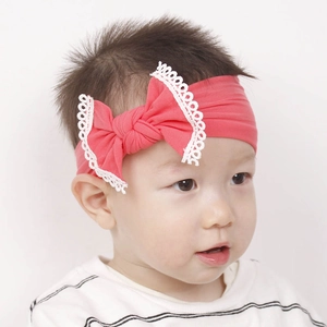 Detail of pink baby nylon headband with large white lace bow on infant model